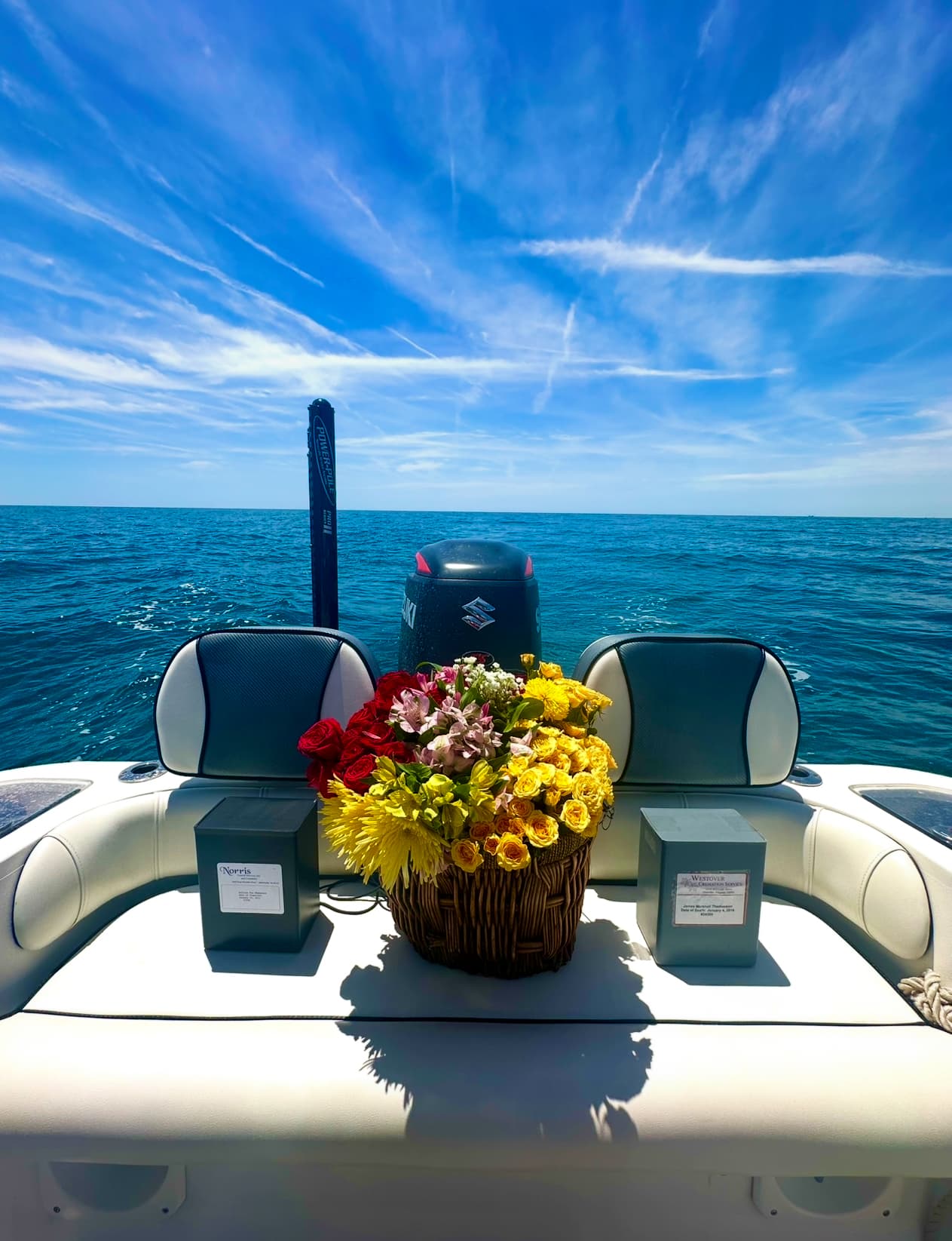 Ceremony basket with flowers and memorial urns aboard the vessel, wide ocean horizon