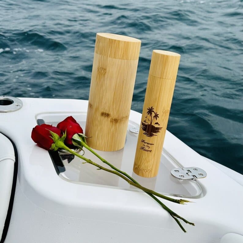 Two bamboo urns with a red rose resting on the boat deck